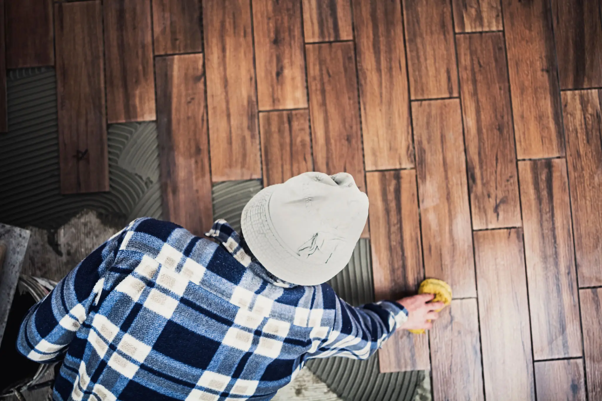 Worker laying wooden tiles with sponge